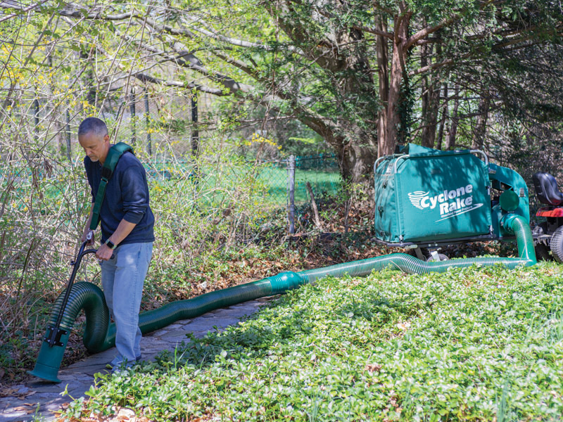 Man using the Estate vacuum to clear leaves from a long stone path