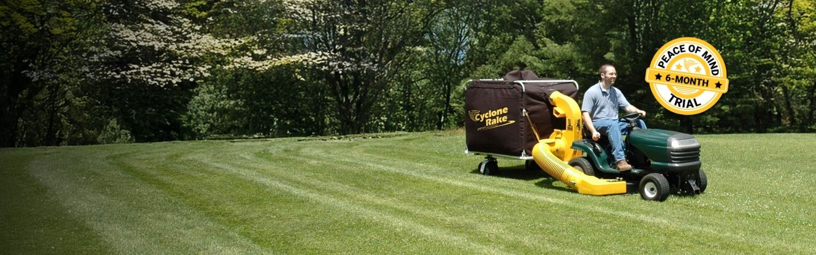 Cyclone Rake lawn and leaf pickup machine being towed by a lawn tractor in a yard in spring