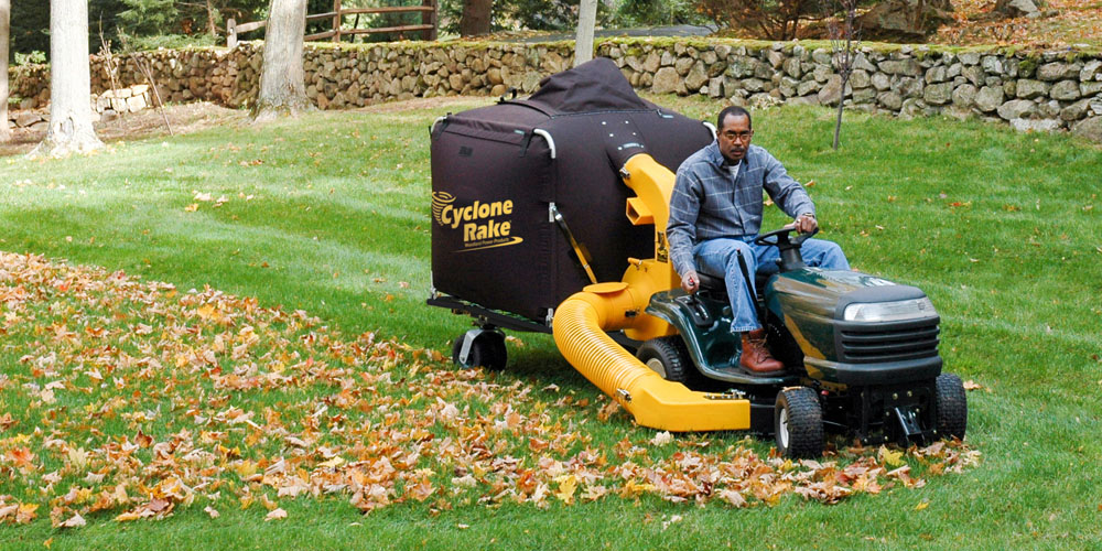 Cyclone Rake tow-behind leaf vacuum hitched to a riding mower clearing leaves in one pass